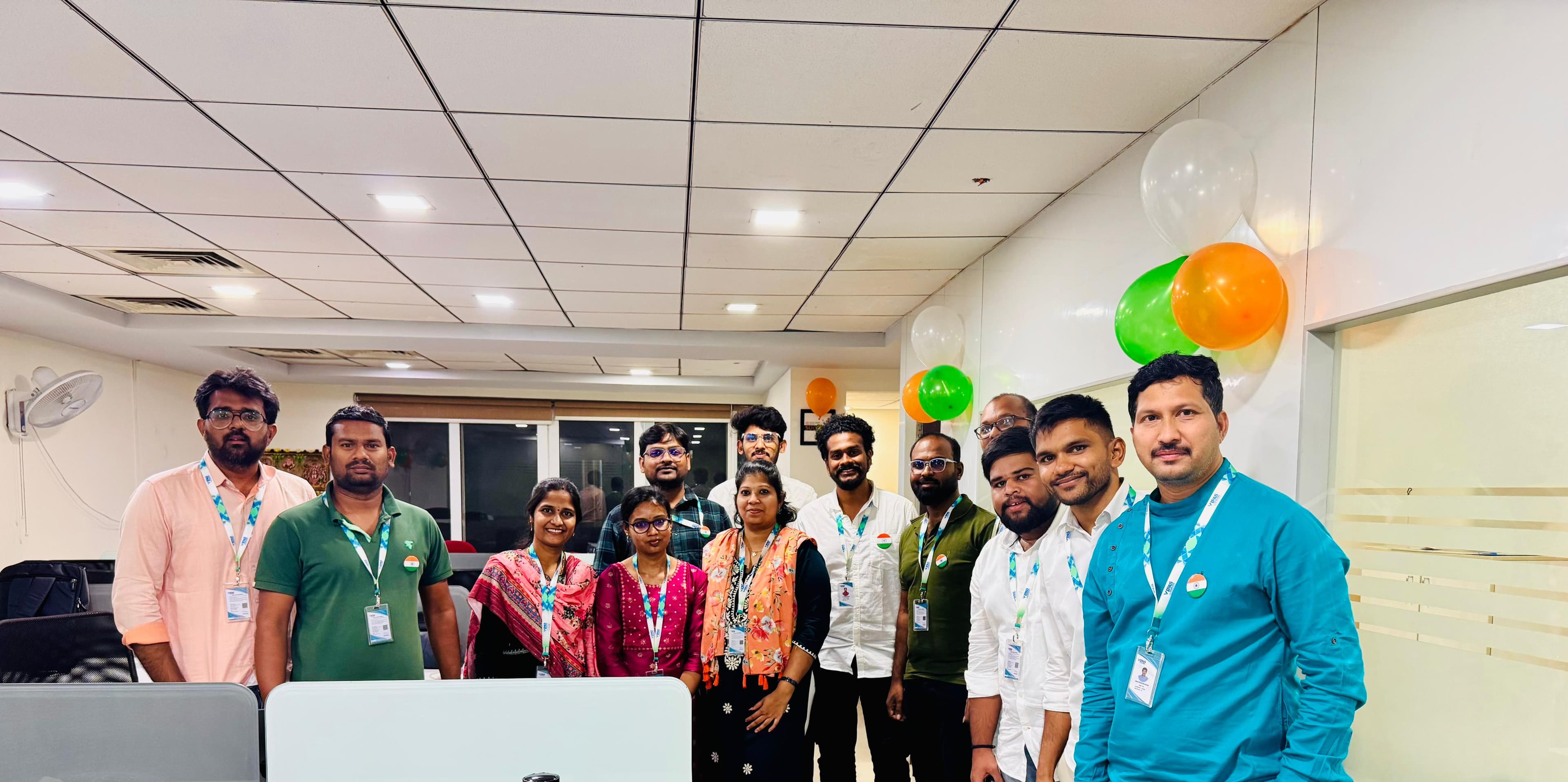 The team posing together in the office, decorated with orange, white and green balloons for Independence Day